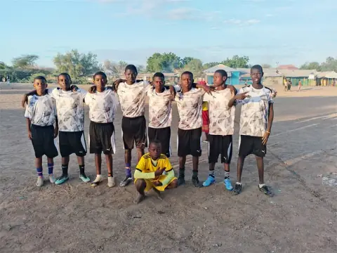Young people lined up together on a football pitch in the evening light